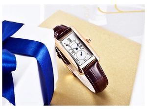 Detail of square gold watch with Roman numerals and brown crocodile leather strap