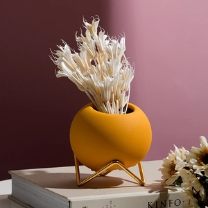 Modern yellow ceramic sphere vase with geometric gold metal base and dried flowers