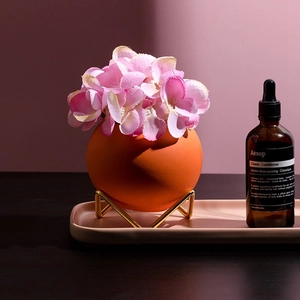Nordic orange ceramic sphere vase with gold metal base and pink hydrangea flowers