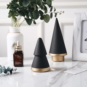 Modern minimalist black and gold ceramic Christmas tree ornaments on marble surface