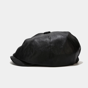 Close-up of black PU leather newsboy cap showing detailed eight-panel texture and short brim