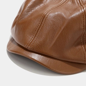 Close-up of brown leather newsboy hat showing fine texture and double stitching detail