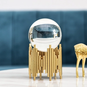 Modern Nordic crystal ball ornament with gold cylindrical metal base on marble surface