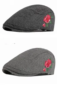 Détail de la broderie rose rouge sur les bérets en laine texturée gris foncé et clair