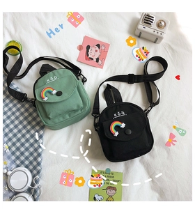 Flat lay of small canvas crossbody bags in green and black with rainbow patches and straps