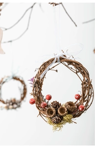 Detail view of a rustic Christmas wreath with pine cones and red berries on white background