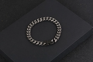 Détail du bracelet gourmette en acier titane gris foncé mat sur un socle noir minimaliste