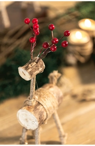 Détail macro d'un élan de Noël en bois avec baies rouges et texture naturelle