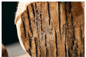 Macro shot of rustic wooden snowman ornament with natural bark texture and burlap edges