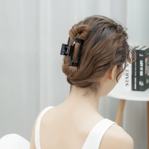 Rear view of a large black hollow geometric hair claw clip used in a bun hairstyle