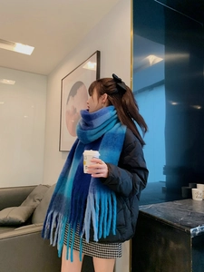 Close-up of blue gradient rainbow plaid scarf with long tassels on a casual wearer