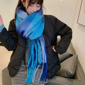 Detail of blue gradient plaid scarf with soft tassels worn over a black winter jacket