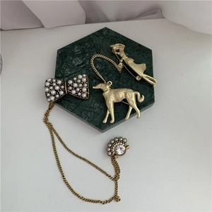 Flat lay of baroque gold pearl bow brooches and vintage charms on green marble