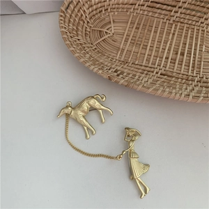 Detailed close-up of a gold-plated vintage French girl walking dog brooch with pearl accents