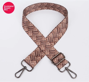 Close-up of adjustable woven shoulder strap with gun-metal hooks and geometric pattern