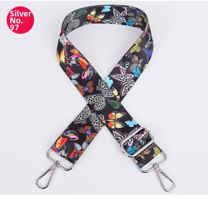 Detail of adjustable nylon bag strap with colorful butterfly pattern and silver metal hooks