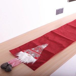 Linen Christmas table runner with gnome pattern and long striped legs on wooden table