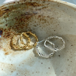 Detail of twisted S925 sterling silver hoop earrings in gold and silver colors