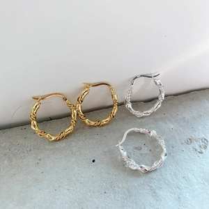 Macro detail of twisted rope texture on 925 sterling silver hoop earrings in gold and silver