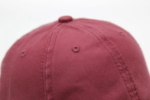 Macro shot of dark red washed cotton twill fabric with stitched ventilation eyelets on cap
