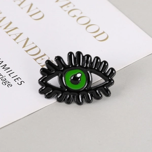 Detailed macro view of the black and green enamel evil eye brooch with long eyelashes
