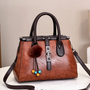 Détail du sac à main marron texture crocodile avec boucle métal et pendentif peluche