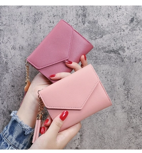 Detail of short tri-fold envelope wallets in plum and pink with heart tassel charms