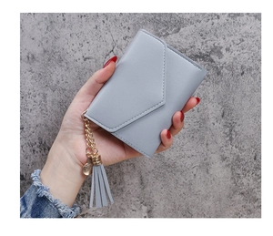 Close-up of light blue trifold wallet with tassel and heart pendant held in hand