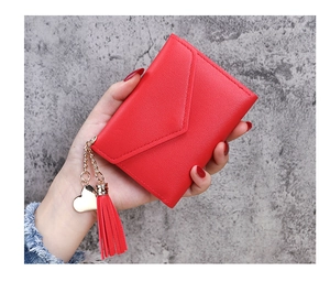 Detail of red tassel pendant and heart charm on a lychee pattern women's wallet