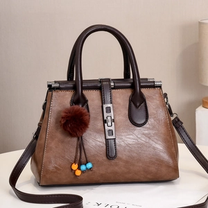 Détail du sac cabas en similicuir marron avec boucle argentée et pompon décoratif