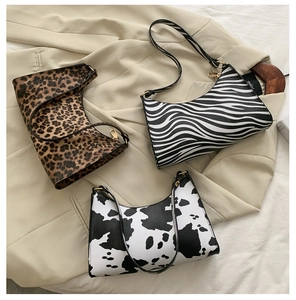 Detailed view of fashion baguette bags in leopard, zebra, and cow prints on a blazer