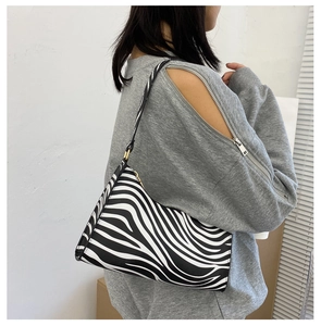 Detail of zebra pattern shoulder bag with a slim strap worn under the arm on white background