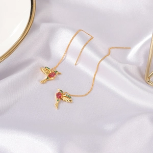 Detail of hummingbird threader earrings with red gemstones on white silk background