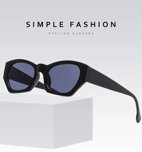 Macro shot of stylish black geometric cat-eye sunglasses with dark blue lenses on a white pedestal