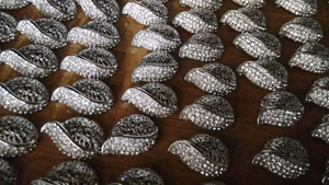 Detailed close-up of shiny silver crescent accessories on a dark wood surface