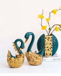 Detailweergave van de donkergroene keramische zwanenfiguren met goudkleurige laag