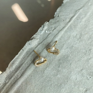 Macro shot of gold safety pin earrings with pearl and crystal pavé on stone base