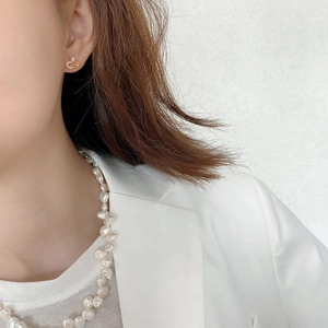Close-up of gold safety pin earrings with pearls and baroque pearl necklace on model