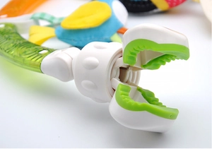 Macro detail of secure white and green plastic clip attachment for baby stroller toy