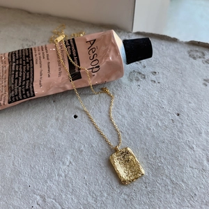 Detail of irregular textured gold pendant on a minimalist geometric necklace for women