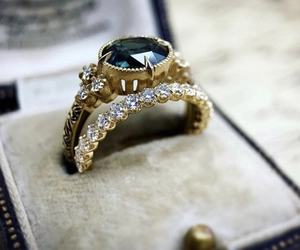 Macro view of gold vintage ring set with oval emerald gemstone and pavé diamonds