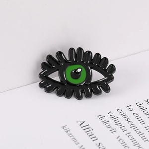 Picasso style cartoon eye brooch with green enamel pupil on a white minimalist background