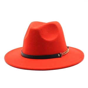 Detail of red fedora hat featuring a black leather band and bold gold metal chain accent