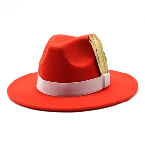 Detail of red wide-brim felt fedora with white ribbon and golden feather ornament
