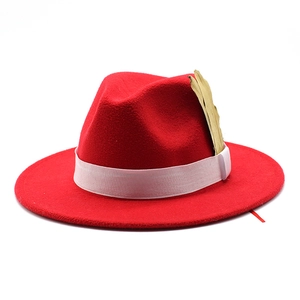 Close-up of red wool fedora hat featuring white ribbon band and gold leaf ornament