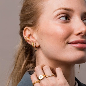 Detailed shot of a gold snake ear cuff and layered rings on a fashion-forward model