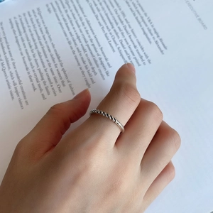 Detailed view of a silver twisted rope ring worn by a model against a magazine backdrop