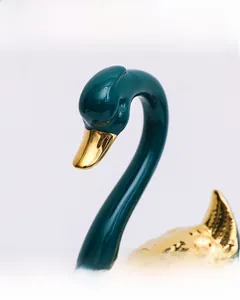 Gros plan sur un cygne décoratif en céramique avec émail cyan foncé et détails dorés fins