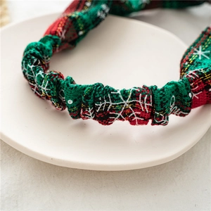 Detail of Christmas plaid headband with snowflake embroidery and gold thread on a tray