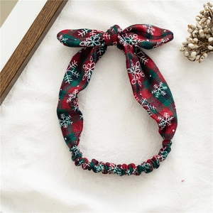 Detail of red and green plaid Christmas headband with white snowflake patterns and bowknot